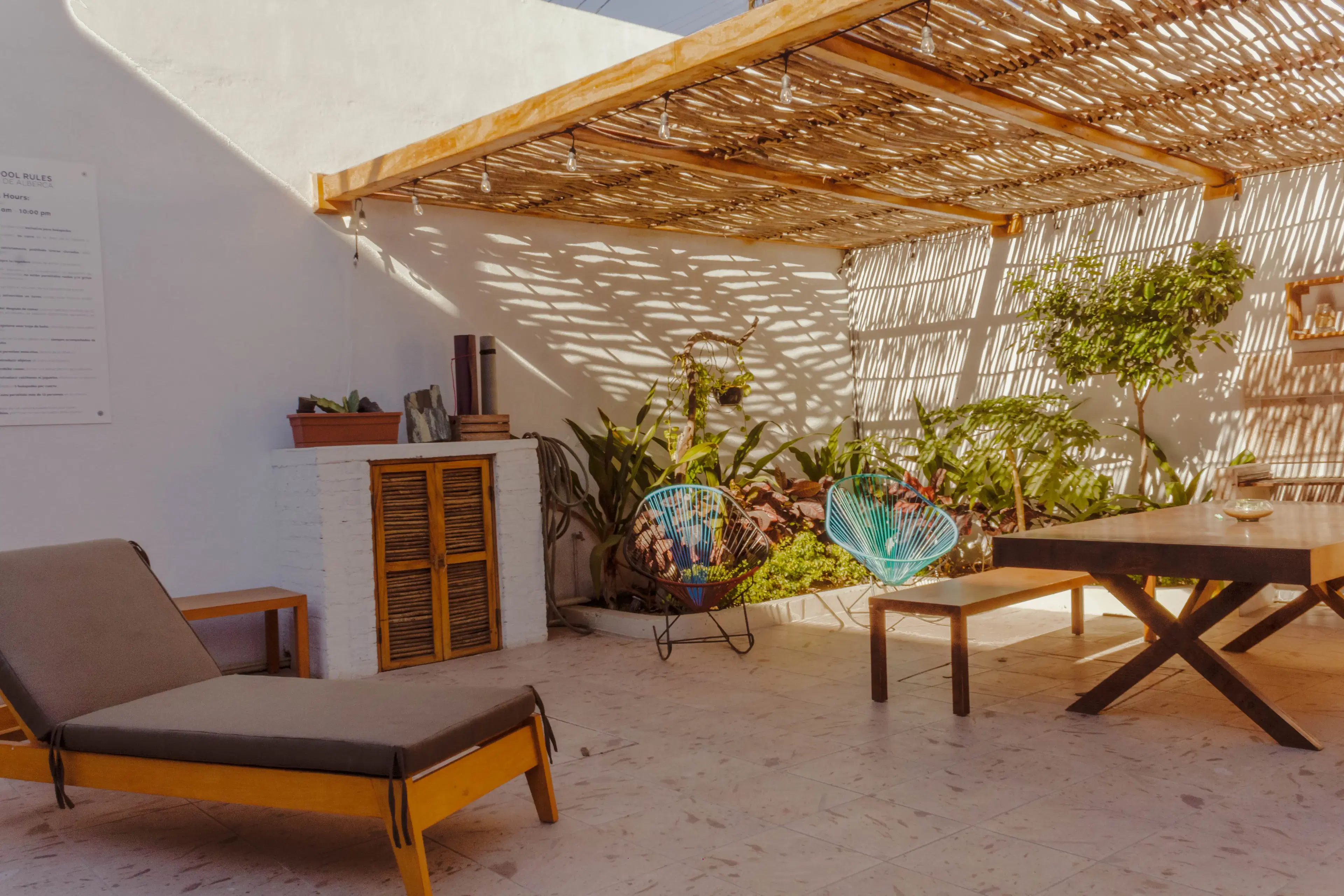 Shaded terrace with lounge chair, Acapulco chairs, and pool rules sign