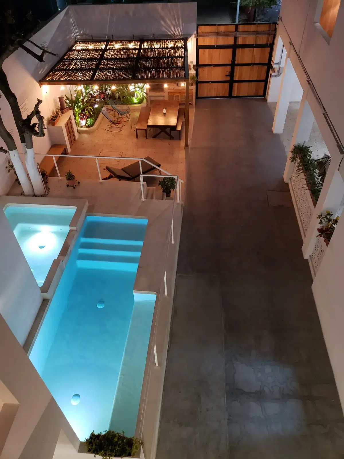 Night view of the courtyard pool, pergola, and string lights